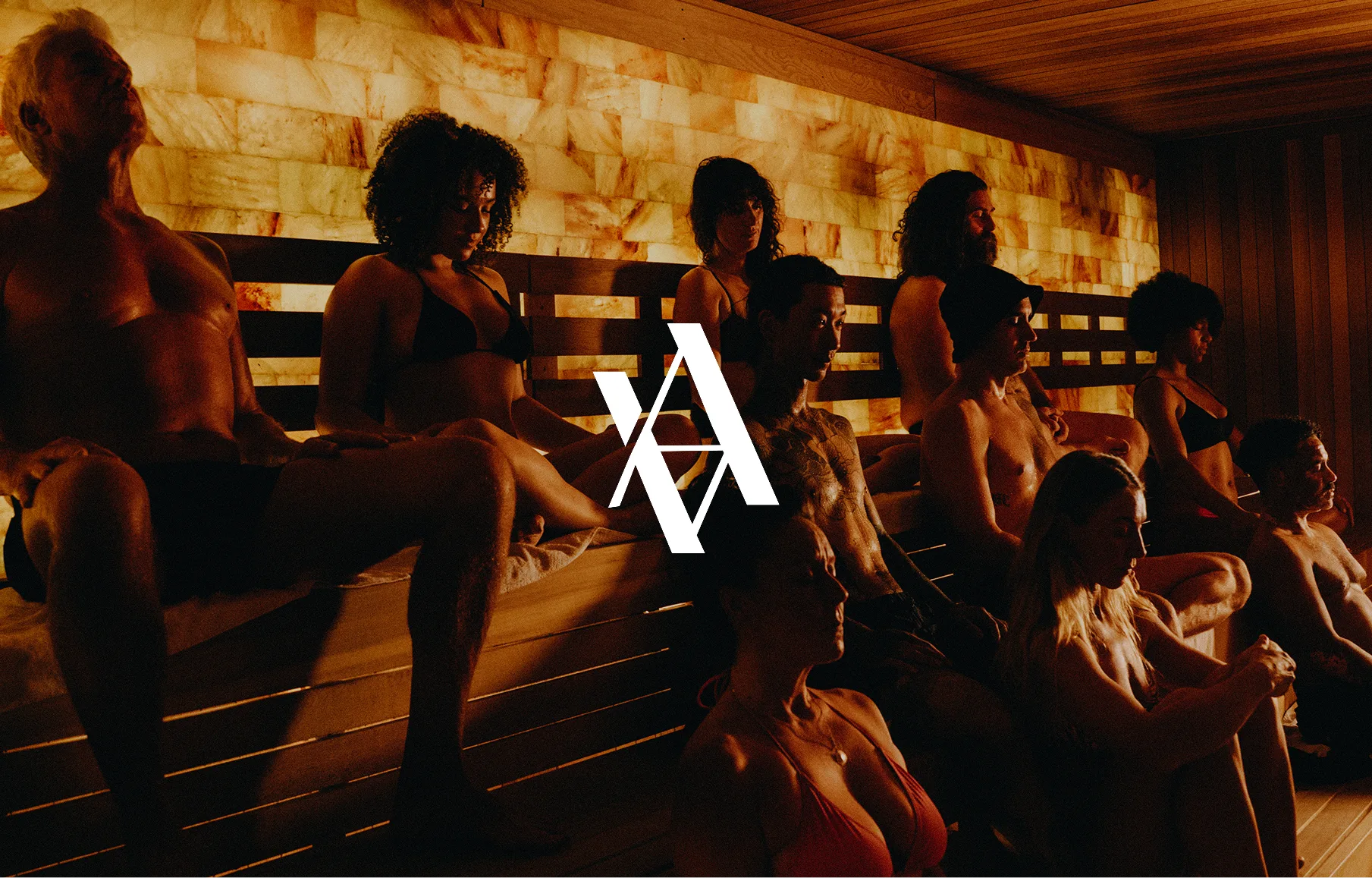 AetherHaus white monogram over a warmly lit sauna gathering